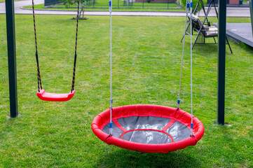 Outdoor Playground with Swings and a Circular Red Rope Swing in a Park