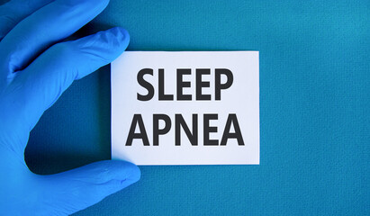 Sleep apnea symbol. Concept words Sleep apnea on beautiful white card. Doctor's hand in blue...