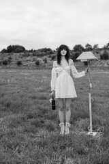 Young woman standing in field holding lamp