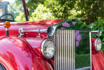 Front view of a vintage luxury car with a shiny red body. 