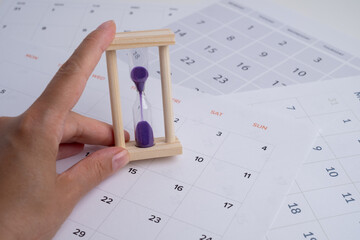 Hourglass and calendar on the table. Deadline. Concept of important time and deadlines