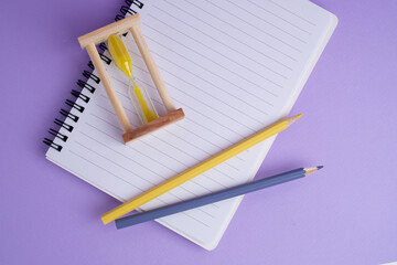 Time management concept: hourglass pencil and notepad. Time for school