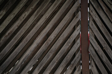 Close-up of weathered wooden diagonal slats forming rustic textured wall or gate with visible...