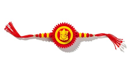 Close up of a rakhi with a red and yellow design featuring an image of lord ganesha in the center