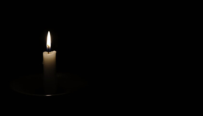 Single white candle lit in darkness representing concept of Valentine’s Day  