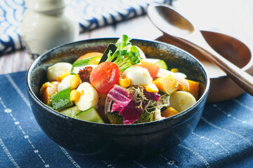 Japanese Garden Salad served in dark bowl with Vegetables, Tofu, cherry tomatoes, corn, cucumber,...