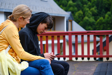 Mother and son sitting together looking at a smartphone