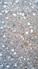 Close-up of gray asphalt surface with small white and dark stones.