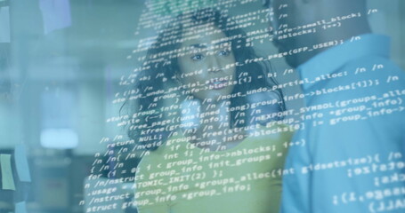 Reviewing team in green and blue shirts standing behind clear code screen at office, with monitors