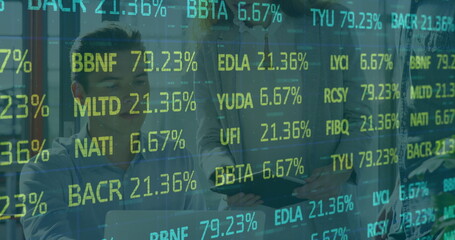 Obraz premium Collaborating team in business attire reviewing stock ticker overlay on tablet in open-plan office