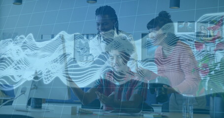 Collaborating team members analyzing data on monitor in office, with coffee mug and notepad