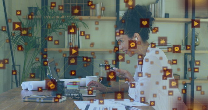 Typing woman in blouse checking smartphone amid social media icons in home office, with laptop