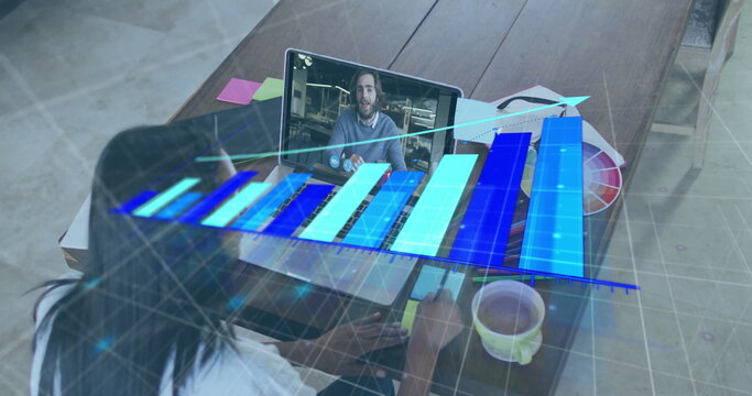 Working designer analyzing holographic bar chart on laptop in home office with color swatch palette