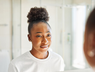 Portrait of a young beautiful black woman in front of mirror in bathroom in morning, skin care,...