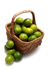 Ripe limes in a wicker basket on a white background. Juicy citrus fruits for fresh drinks, desserts and healthy food.