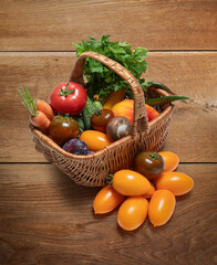 Various vegetables in a wicker basket on a wooden background. Perfect image for farm products or eco advertising.
