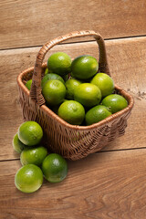 A basket of limes on a wooden surface. Natural fruits, organic style and cozy atmosphere.