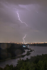 Lightning in the sky above the forest during a summer thunderstorm
