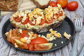 Delicious avocado toast with scrambled eggs and tomatoes