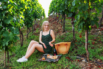 Excited young woman laughing in vineyard during picnic, joyful countryside escape.