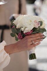 Elegant bridal bouquet held by a woman's hand in a romantic outdoor setting during a wedding...