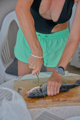 young woman cleaning and cutting fresh fish on a cutting board