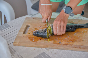 young woman cleaning and cutting fresh fish on a cutting board