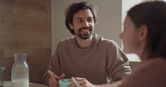 Over the shoulder stubbled father talks to his teenage daughter during a family breakfast in the kitchen in the morning. Family breakfast and chatting in the kitchen in the morning