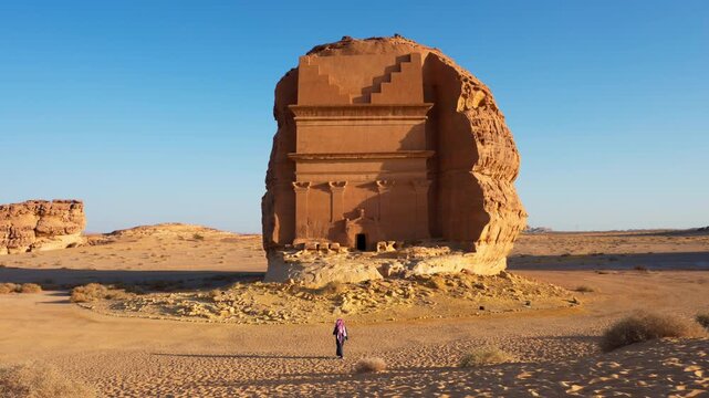 4k Video of Arab Saudi man standing in front of Qasr al Farid, lonely castle, tomb in Archeological site Madain Saleh, Al-Ula, Hegra, Saudi Arabia