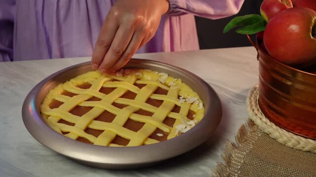 Seamless apple pie lattice top preparation by woman in purple dress