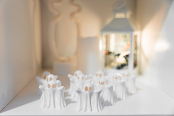 A group of small white ghost figurines arranged in rows with warm lantern light, perfect for...