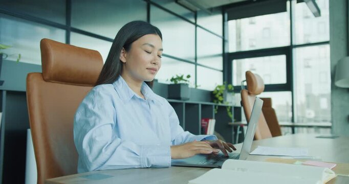 A young woman typing on a laptop in a stylish office space, showcasing concentration and productivity.