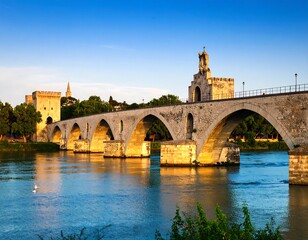 Obraz premium Ancient stone bridge over a serene river at sunset