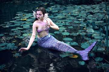 Fototapeta premium Mermaid lounging in serene pond surrounded by lily pads on a peaceful afternoon