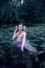 Fototapeta premium Mermaid lounging in serene pond surrounded by lily pads on a peaceful afternoon