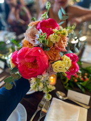 A close up of a beautiful centrepiece of flowers in a vase on a table for a wedding.