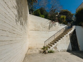 Old Mediterranean stone staircases surrounded by greenery and blue sky, traditional architecture
