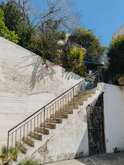 Old Mediterranean stone staircases surrounded by greenery and blue sky, traditional architecture