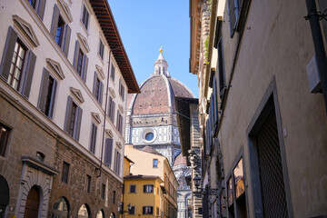 Perspective view of Brunelleschi dome through traditional Italian street with old houses Florence
