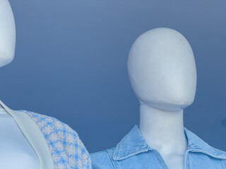Close-up of faceless fashion mannequins in modern clothing store window with minimalist style and...