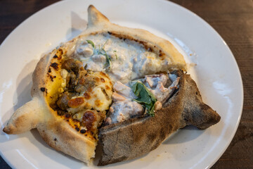 Three flavors of Adjaruli Khachapuri are filled with chashushuli (a veal stew with tomatoes),...