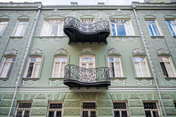 Green art Nouveau building facade showcases ornate iron balconies. Early 20th century style popular in Europe spread to Tbilisi, a melting pot of cultures.