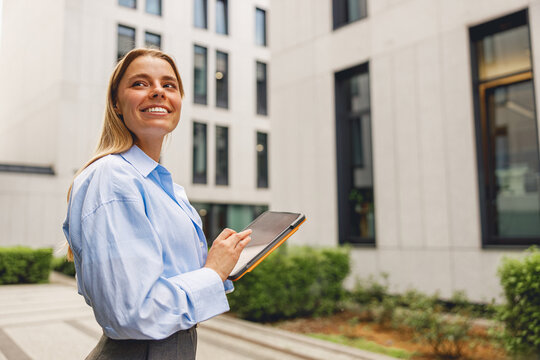 A confident businesswoman is situated in a modern environment, diligently jotting down notes on her tablet