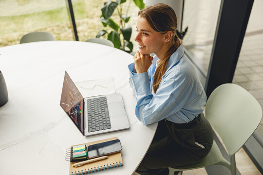 A dedicated and focused woman diligently working on her laptop amidst stationery items in a stylish modern workspace