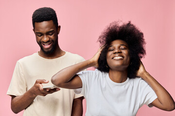 Happy young African couple enjoying time together against a pink background, highlighting joy and...