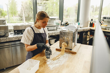A truly talented chef is skillfully creating fresh pasta using a pasta machine in a stylish and modern kitchen setting