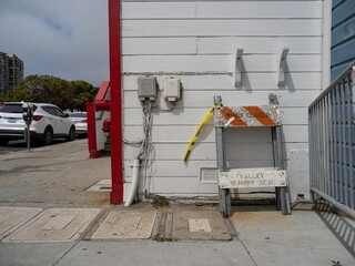 Weathered white building exterior with road closure barrier and yellow caution tape showing urban...