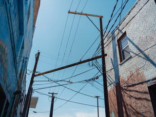 Electrical power lines and utility poles intersecting between urban brick buildings creating...