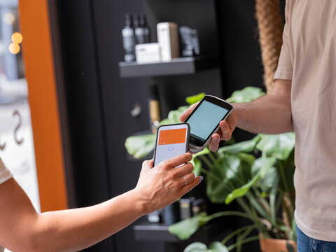 Close-up of contactless payment transaction between smartphone and payment card in contemporary environment