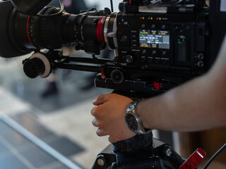 Close-up of hands operating professional video camera controls with focus on technical equipment
